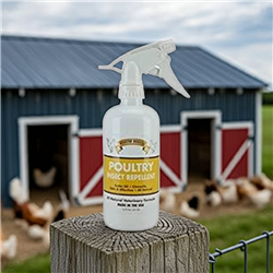 Rooster Booster Poultry Insect Repellent bottle sitting on a wooden fence post with a chicken barn in the background